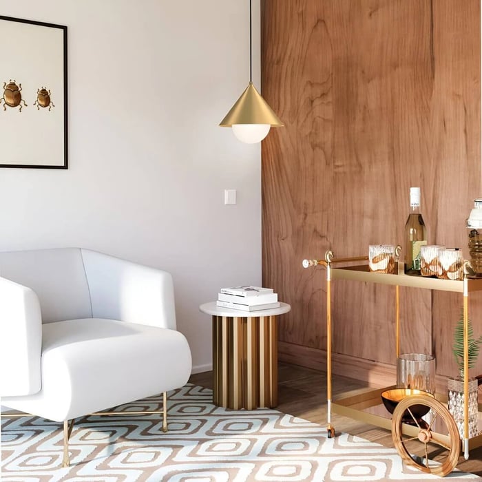 Modern living room vignette with a white curved armchair, brass cone pendant light, round striped side table, gold bar cart, and warm wood accent wall on a patterned rug.