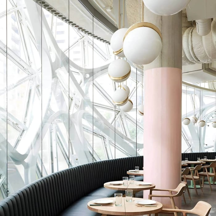 Row of globe pendant lights along a curved banquette in a modern café interior.