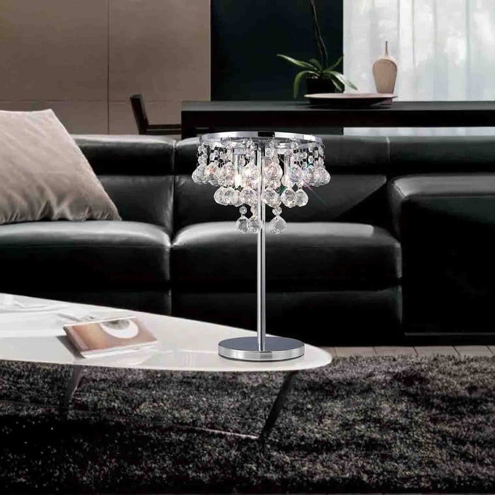 Round white globe table lamp with a brass accent on a dark shelf styled with stacked books and white ceramic vases.