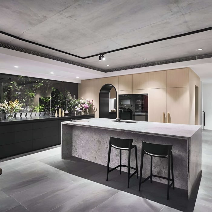 High-end kitchen with a stone island, timber cabinetry, concrete ceiling, and a mix of recessed downlights and track-style spot lighting.