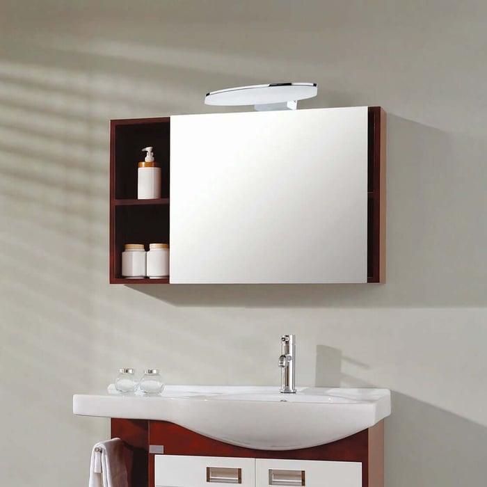 Bathroom vanity with a large mirrored cabinet and light above, built-in side shelving with containers, and a white sink with a chrome faucet.