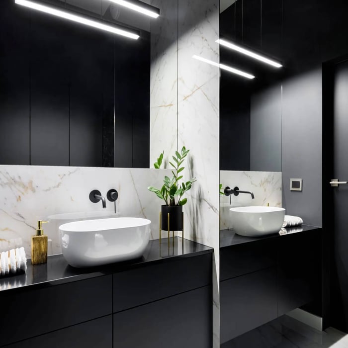 Modern bathroom with black cabinetry and marble splashback, featuring bright linear ceiling lighting above a double vanity and mirror.