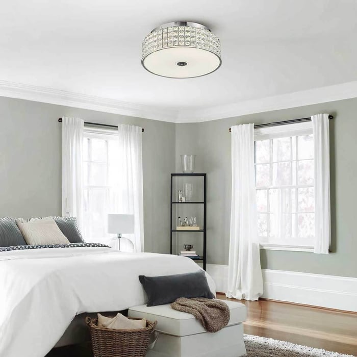 Bright neutral bedroom with a crystal flush ceiling light, white curtains and a neatly made bed beside large windows.