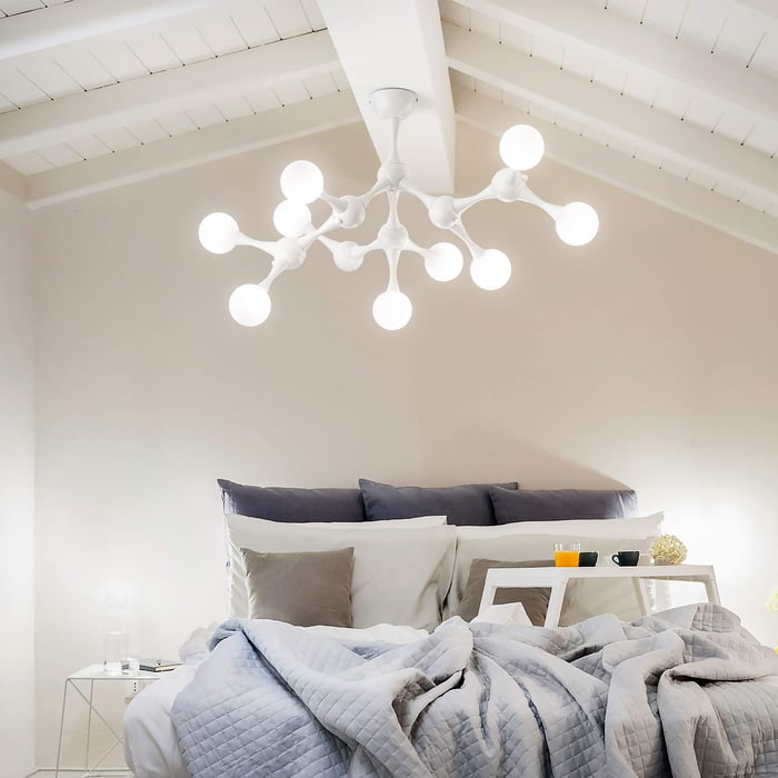Elegant white chandelier with classic curved arms and candle-like bulbs, creating ambient bedroom lighting.