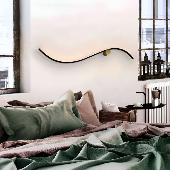 Cosy bedroom with a curved wall light above the bed, soft bedding, and large industrial-style windows.