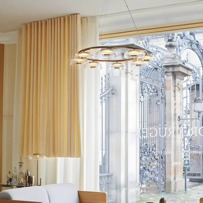 Gold ring pendant with clear glass dome shades suspended in a bright, modern interior.