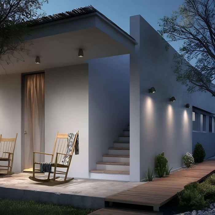 Modern house exterior with two ceiling downlights under a porch roof and wall-mounted lights washing a side walkway.