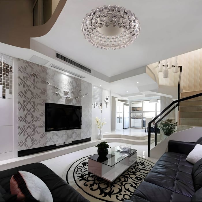 Double-height living room with cascading bubble glass pendant lights, grey sectional, and tall windows with black framing.