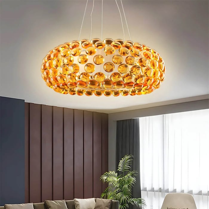Oval chandelier made of amber glass discs, glowing above a contemporary living space.