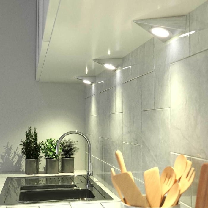 Triangle under-cabinet LED lights illuminating a tiled kitchen backsplash above the sink.