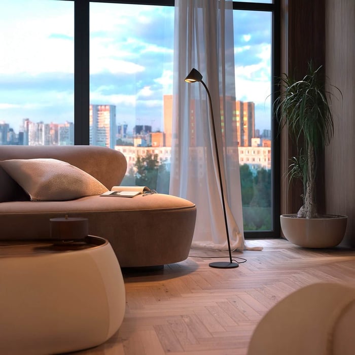 Sleek black floor lamp with angled cone shade beside a window and modern sofa.