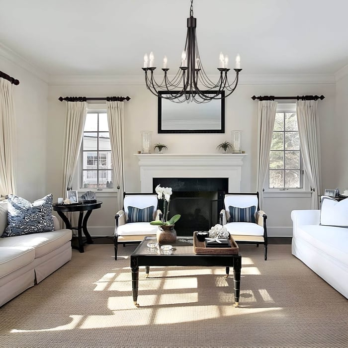 Black wrought iron chandelier with candle-style bulbs above a modern living room fireplace.