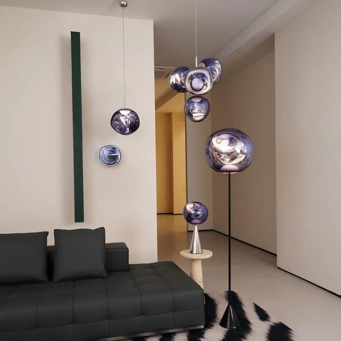 Minimalist living room with smoky violet glass globe lights pendant, wall, floor, and table fixtures glowing beside a black modular sofa.