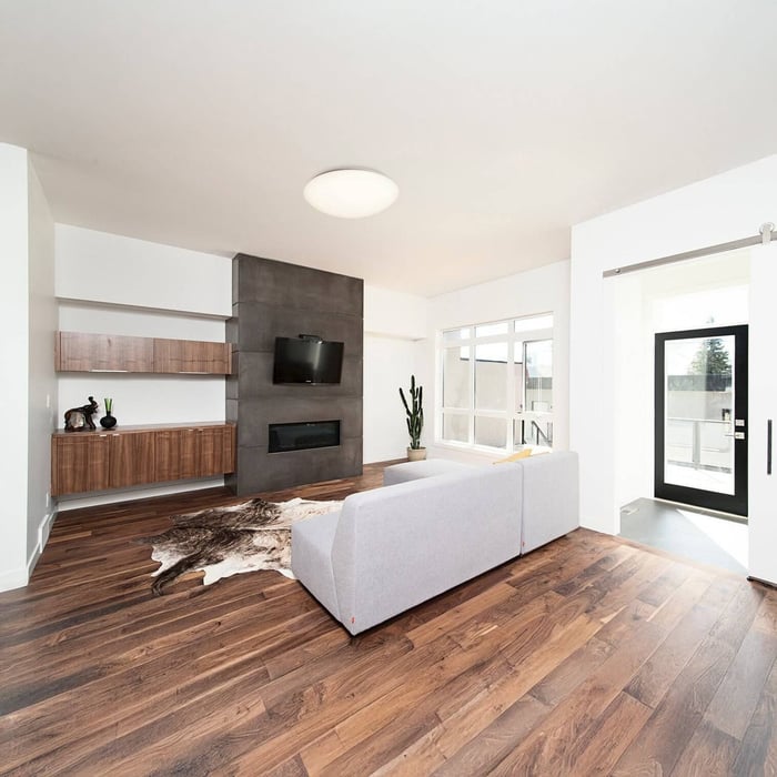 Modern living room with wood floors, gray sofa, and circular flush ceiling light.