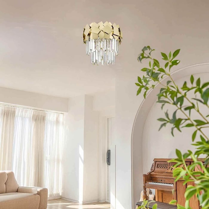 Light-filled lounge with a gold-and-crystal ceiling lights near an arched doorway and indoor greenery.