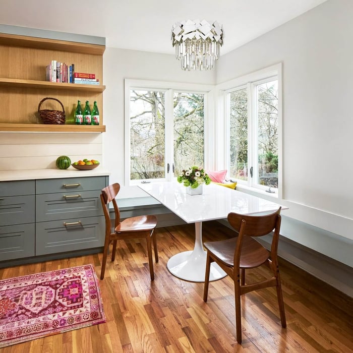 Dining area lighting — Bright dining nook with a white tulip table, wooden chairs, and a modern chandelier with reflective hanging crystals.