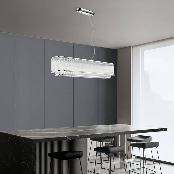 Rectangular crystal chandelier with chrome frame suspended above a black marble kitchen island.