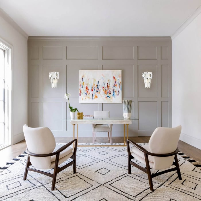 Symmetrical crystal wall sconces mounted on gray paneled walls above a glass desk and chairs.
