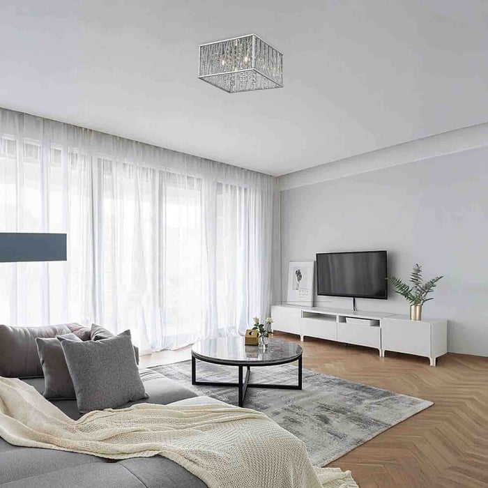Soft neutral living room with sheer white curtains, grey sofa, round coffee table, and a small square crystal flush-mount ceiling light.