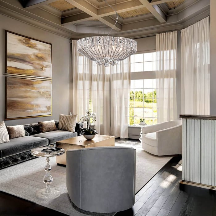 Elegant crystal chandelier in a cozy living room with velvet sofa, modern chairs, and large windows with flowing curtains.