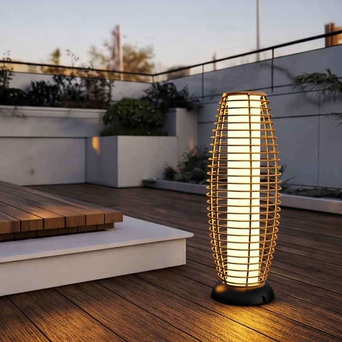 Rattan cage outdoor floor lamp lighting a rooftop deck with raised platform and planters.