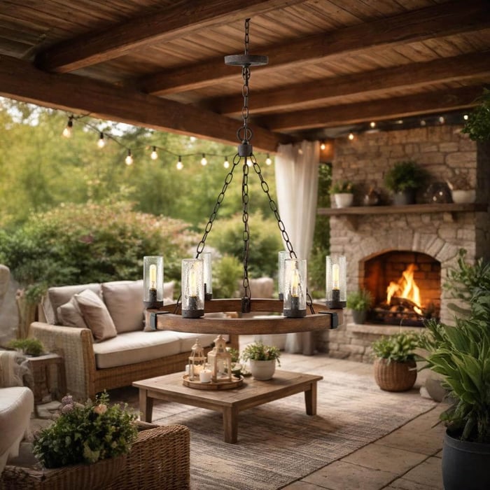 Wood-and-metal ring outdoor chandelier with glass cylinder shades over a cosy covered patio seating area.