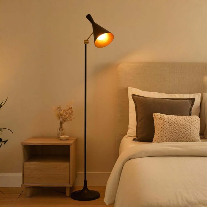Warm-lit industrial floor lamp next to a bed and simple wooden nightstand for cozy bedside reading.
