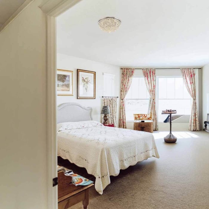 Traditional bedroom with a crystal ceiling flush light and patterned curtains, giving a cosy, even room glow.