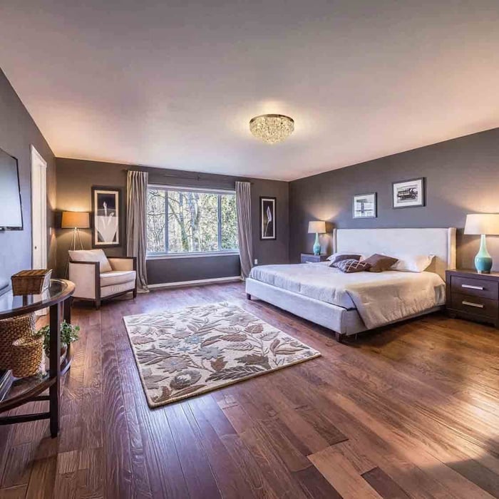 Wide bedroom with crystal pendant and matching bedside lamps, grey walls and large window creating soft layered lighting.