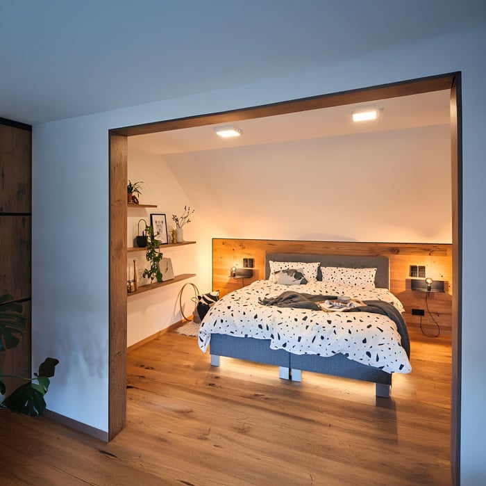 Attic-style bedroom with wood accents, recessed ceiling lights, and soft wall sconces.