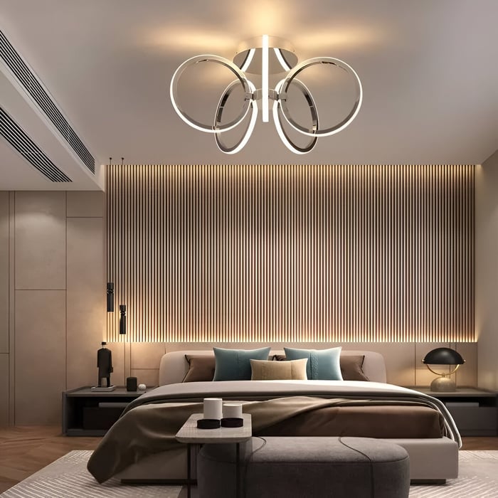 Modern bedroom with LED ring chandelier and backlit slatted headboard wall.