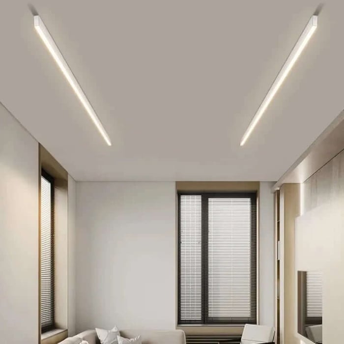 Minimal living space with slim recessed linear ceiling lights and tall windows, showing clean, modern ambient lighting lines.