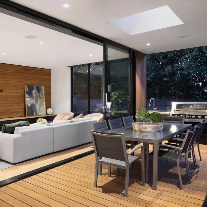 Open-plan dining and living space with a flush square ceiling LED panel light in a contemporary interior.
