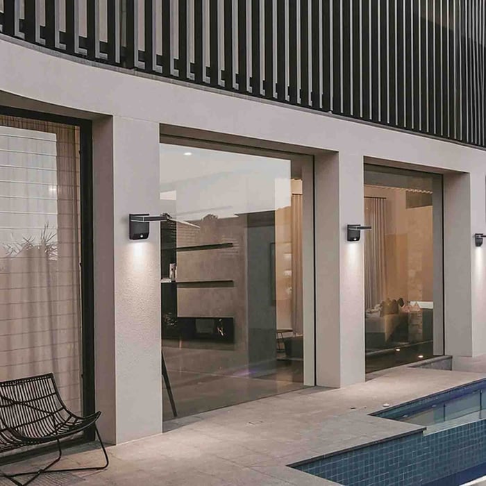 Modern entry courtyard at sunset with sleek outdoor wall sconces lighting a straight stepping-stone path.