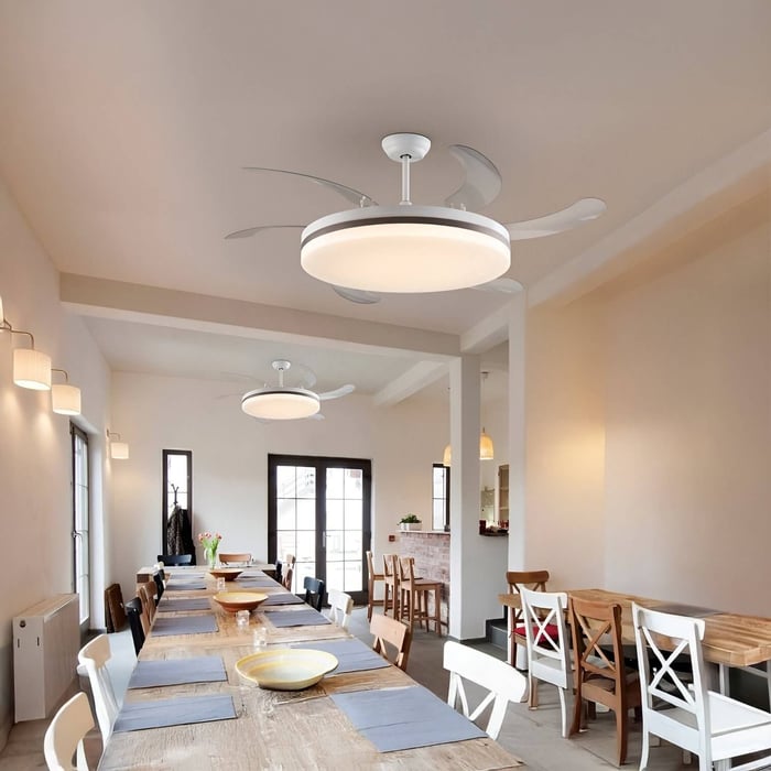 Long dining table setup with matching ceiling fans, light wood accents, and uniform soft white wall sconces throughout.