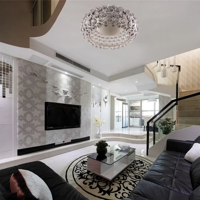 Elegant living room with a crystal disc chandelier, patterned accent wall, and black leather seating.