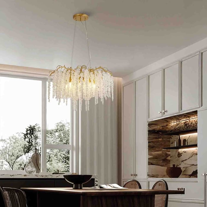 Gold chandelier with cascading crystal strands hanging above a dining table in a bright kitchen-diner.