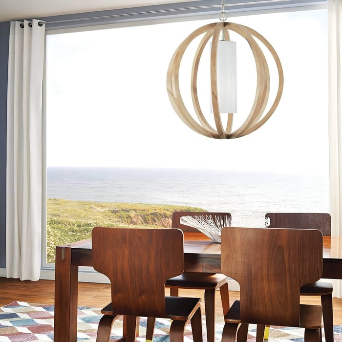 Coastal dining room with wooden chairs, a minimalist table, and a natural wood orb pendant light overlooking the ocean.