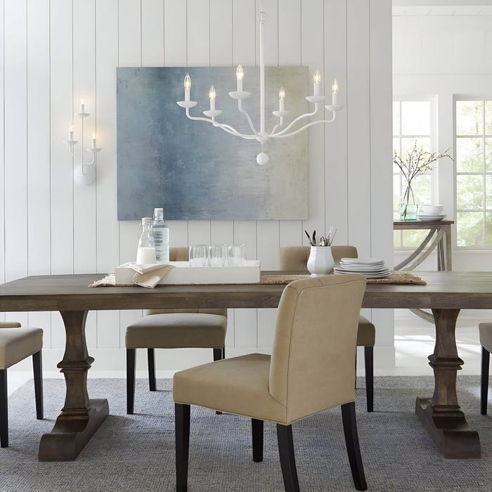 Minimalist white dining room with farmhouse-style wood table and white candelabra chandelier.