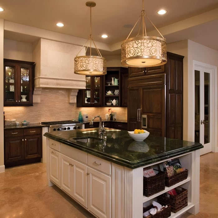 Classic kitchen with a green marble island, white cabinetry, and two ornate drum-shaped chandelier lights hanging over the counter.
