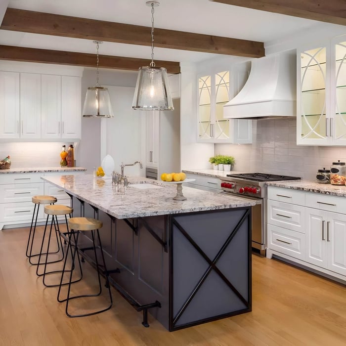 Modern kitchen with marble island, industrial pendant lights, and wood beam ceiling.