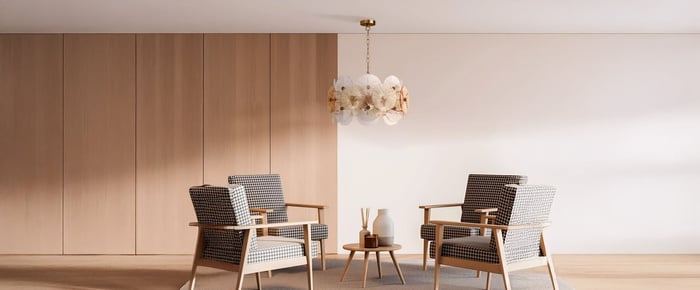 A living room setting featuring a hanging pendant light with decorative discs, positioned over a small wooden coffee table and surrounded by patterned armchairs.
