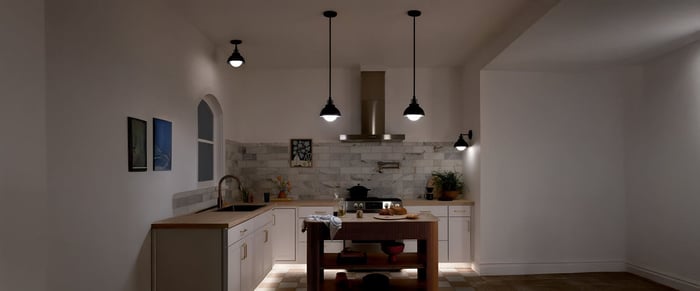 Open kitchen with marble island, five pendant kitchen lights hanging above, built-in appliances, and neutral cabinetry.