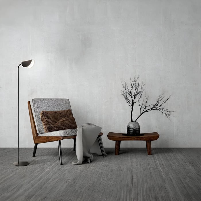 minimalist black reading lamp beside a mid-century wood chair and sculptural table in a neutral room