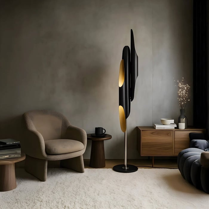 Sculptural black and gold floor lamp in a moody modern living room with a beige lounge chair, wooden side tables, low wood credenza, and a plush light rug.