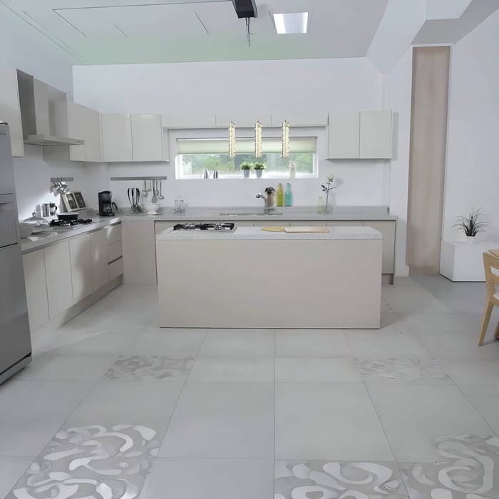 Bright all-white kitchen with a large central island and three slim crystal pendant lights hanging in front of a wide window.