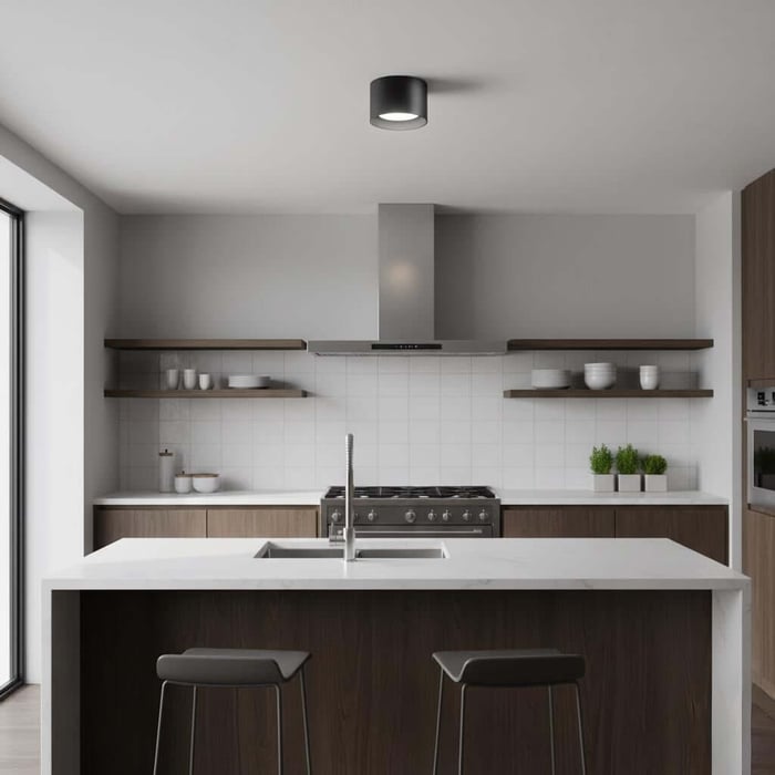 Minimal kitchen with a large white waterfall island, wood cabinetry, open shelves, and a single black surface-mounted downlight overhead.