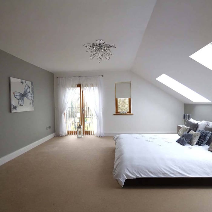 Bright loft-style bedroom with a decorative ceiling light, skylights and neutral décor for airy ambient lighting.