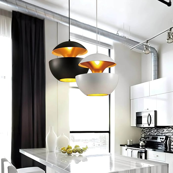 Kitchen island with two dome pendant lights in black and white, casting warm light onto a marble worktop.