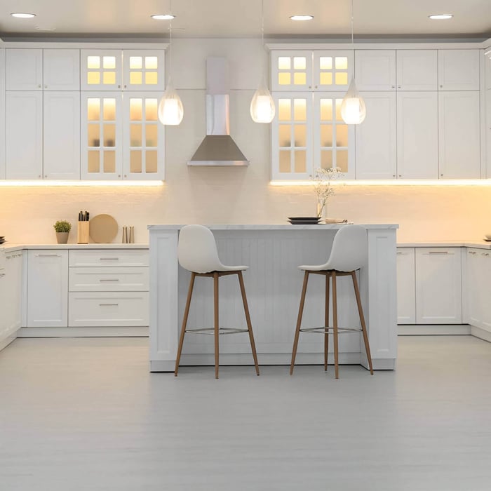 Spacious white kitchen with tall stools and three teardrop-shaped pendant lights over the island.